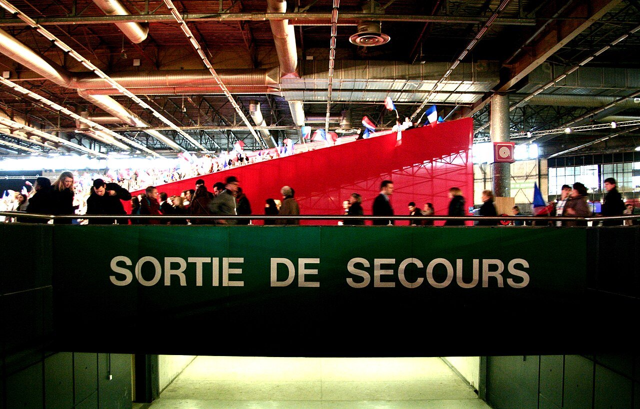 Panneau lumineux de sortie de secours au-dessus d'une porte dans un hall